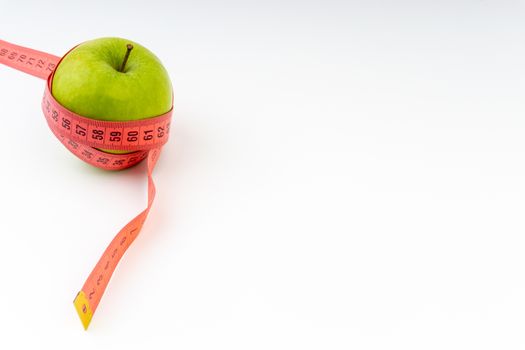 Green apple with red measuring tape. Health care and body fitness concept