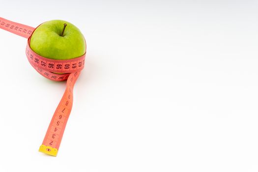 Green apple with red measuring tape. Health care and body fitness concept