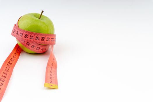 Green apple with red measuring tape. Health care and body fitness concept