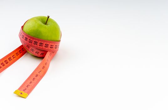 Green apple with red measuring tape. Health care and body fitness concept