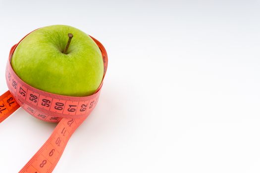 Green apple with red measuring tape. Health care and body fitness concept