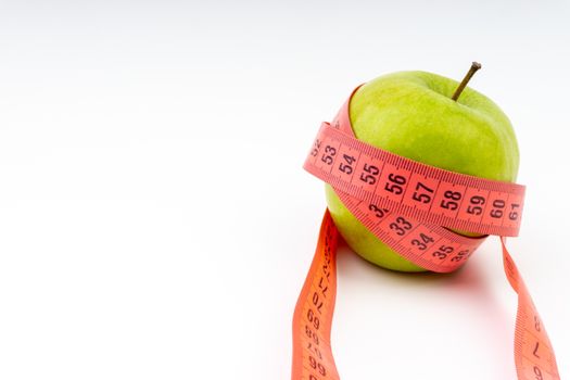 Green apple with red measuring tape. Health care and body fitness concept