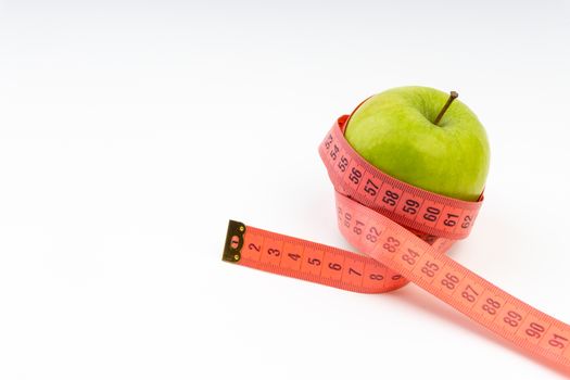 Green apple with red measuring tape. Health care and body fitness concept