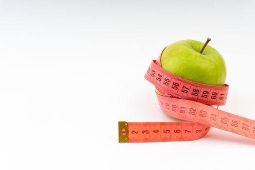 Green apple with red measuring tape. Health care and body fitness concept