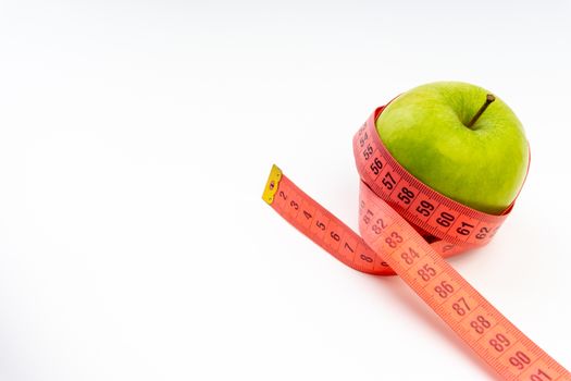 Green apple with red measuring tape. Health care and body fitness concept