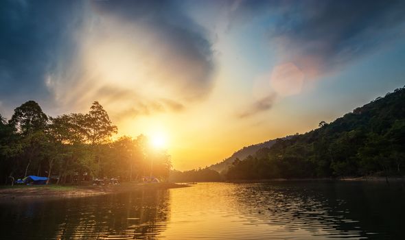 landscape of river view during the sunrise time with many colorful camping tent at campsite