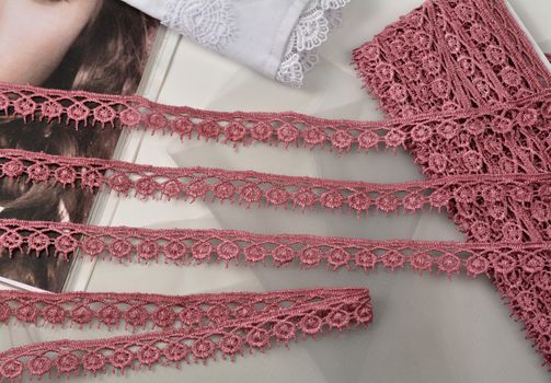 Tapes of pink gentle guipure, beauty lace fabric on light background. Elastic material. Using for Atelier and needlework store.