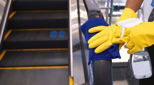 Staff cleaning the escalator hand rail in department store to prevent the spread of pandemic Covid-19 and Coronavirus, healthcare and hygiene concept