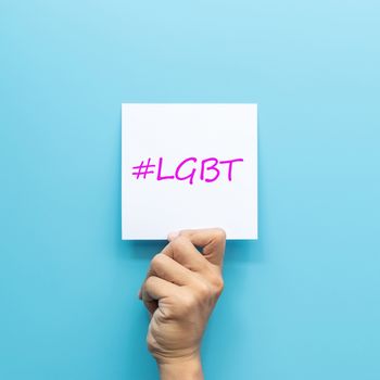 hashtag #LGBT on white paper in hand isolated on blue background