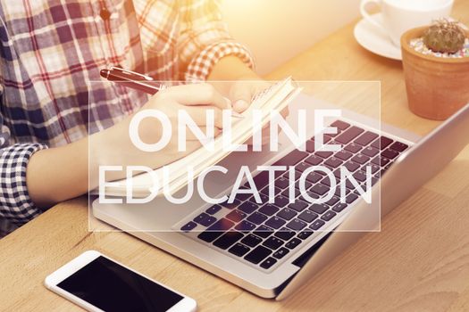 online learning course concept. student using computer laptop for training online and writing lecture note in notebook with text online education on top layer. distance education