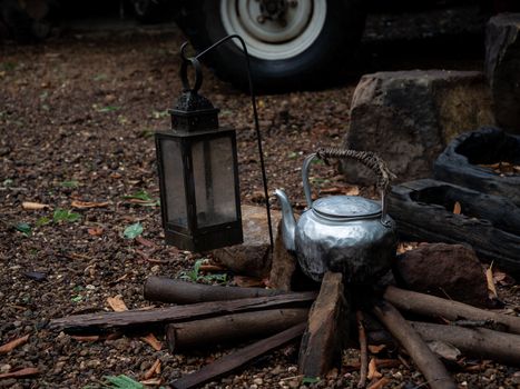 Old kettle on wood in camping outdoor in rainforest background.