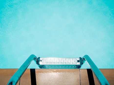 Outdoor swimming pool background minimal style. Top view of grab bars ladder in the blue swimming pool with copy space.