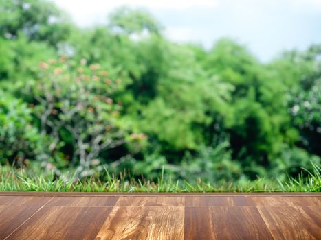 Empty brown wood pattern floor with blurred green spring garden landscape background.