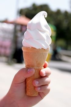 Child hand holding delicous vanilla ice cream cone