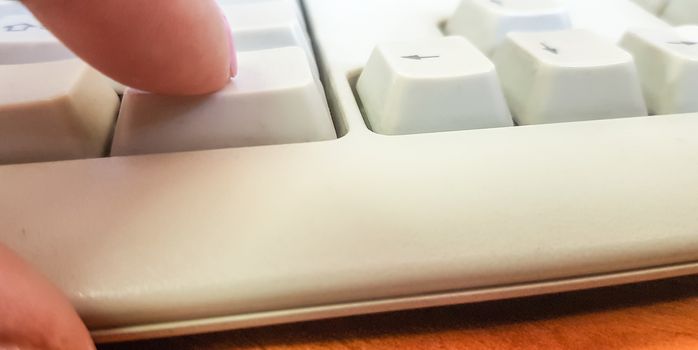 Female finger on a white keyboard, close-up.