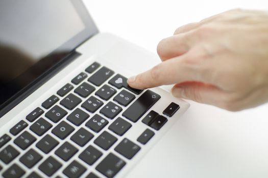 Technology also applies to emotional relationships: a woman's hand is about to press a key on a laptop keyboard with a stamped heart