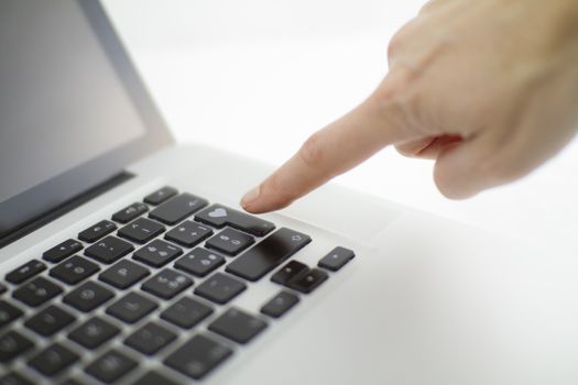 Technology also applies to emotional relationships: a woman's hand is about to press a key on a laptop keyboard with a stamped heart