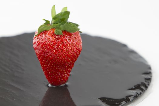Close-up of a strawberries isolated on a wet round slate plate on a white background shot in high angle view with selective focus
