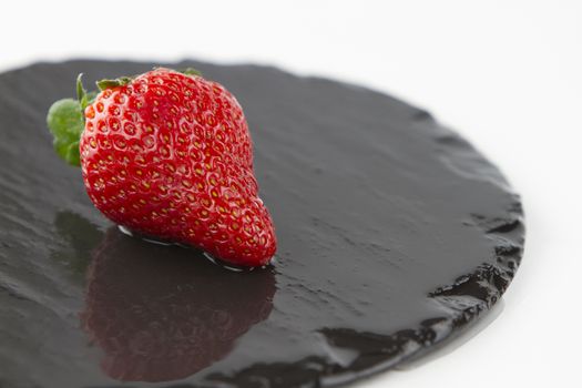 Close-up of a strawberries isolated on a wet round slate plate on a white background shot in high angle view with selective focus