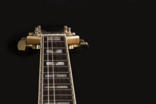 Vintage archtop guitar in natural maple close-up high angle view on black background, rosewood fingerboard with frets and fret markers detail in selective focus