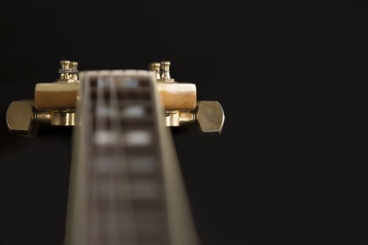 Vintage archtop guitar in natural maple close-up high angle view on black background, rosewood fingerboard with frets and fret markers detail in selective focus