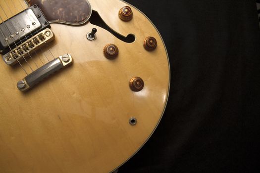 Vintage archtop guitar in natural maple close-up from above on black background