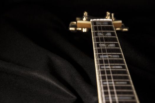 Vintage archtop guitar in natural maple close-up high angle view on black background, rosewood fingerboard with frets and fret markers detail in selective focus