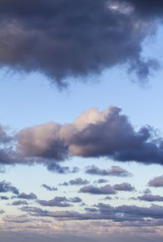 Impressive sky at sunset with layers of clouds tinged with pink that slope down towards the horizon