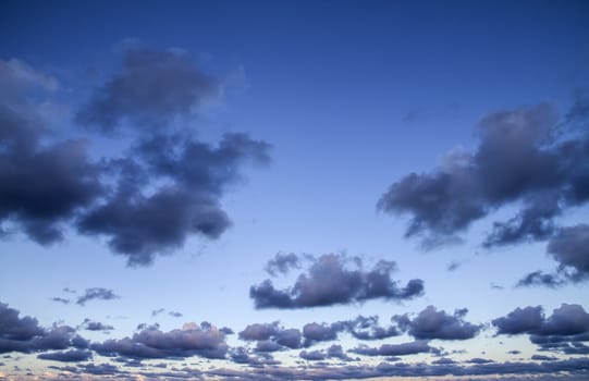 Impressive sky at sunset with layers of clouds tinged with pink that slope down towards the horizon