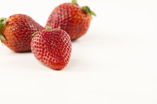Close-up of three strawberries isolated on white background shot in high angle view with selective focus