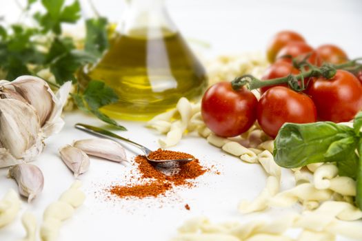 Close-up of italian typical pasta recipe: handmade durum wheat flour pasta, tomatoes, garlic, extra virgin olive oil, ground chili, parsley and basil on white background