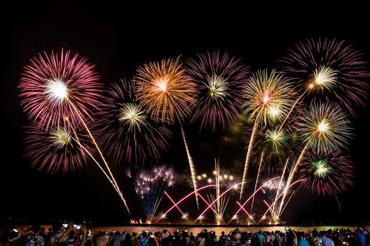 cheering crowd watching colorful fireworks and celebrating on the beach during festival