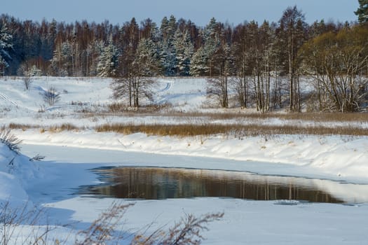 Winter landscape, ravine river and snowy field and forest