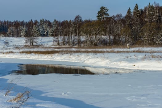 Winter landscape, ravine river and snowy field and forest