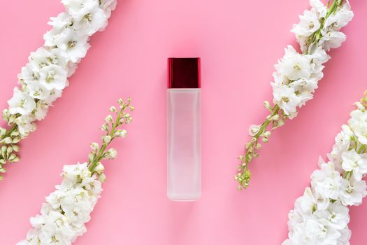 natural beauty skincare product. luxury cosmetic bottle container with white spring flower herbal on pastel pink background. blank label for branding mock-up, top view, flat lay