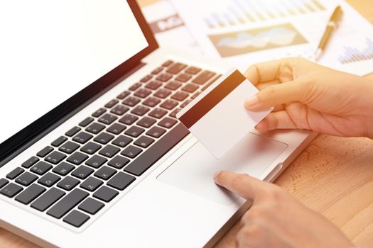 e-commerce and shopping online concept. woman holding a credit card and purchase making online payment via computer notebook with blank white screen in workplace