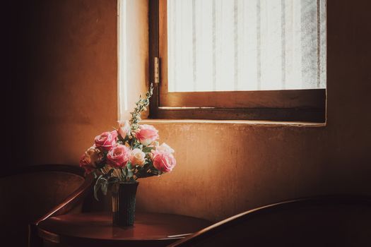 plastic flowers in old pots get sunlight from the side of the window.