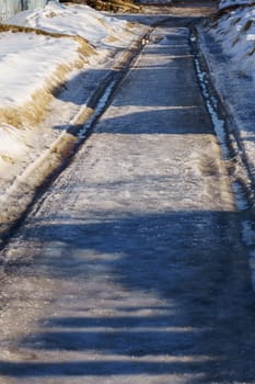 winter road covered with snow and ice with puddles and ruts, vertical shot