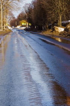 winter road covered with snow and ice with puddles and ruts, vertical shot