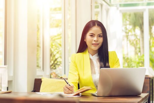 portrait of beautiful and confident Asian business woman in working with notebook laptop and book manage job work at workplace. happy businesswoman concept