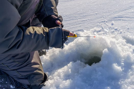hands of a fisherman, a winter fishing pole and a hole in the ice, an ice fishing plot