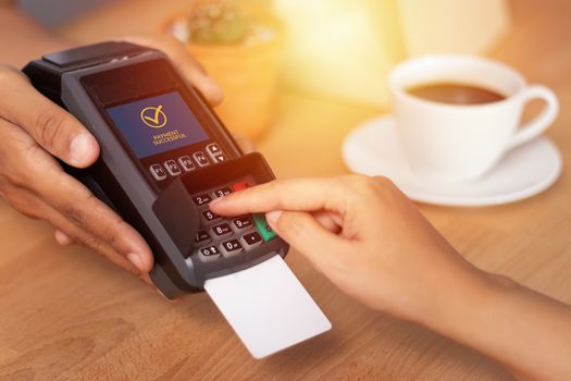 close up of hand entering credit card pin code for security password in credit card swipe machine at point of sale terminal in shop during shopping time