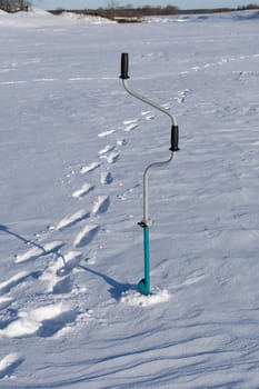 drill for holes in the ice and traces of the fisherman in the snow on a sunny winter day