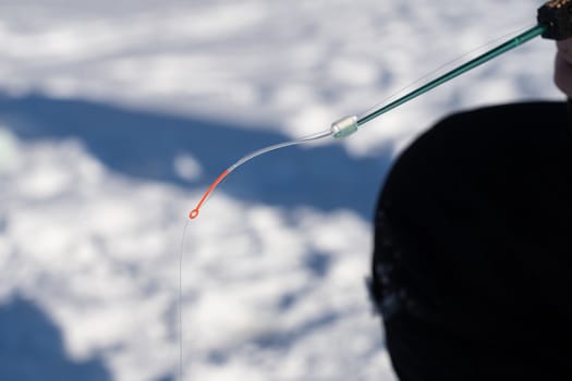 winter rod and angler's hands over the hole in the ice