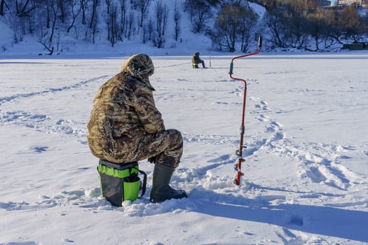 fisherman and a drill in the ice, a plot on ice fishing