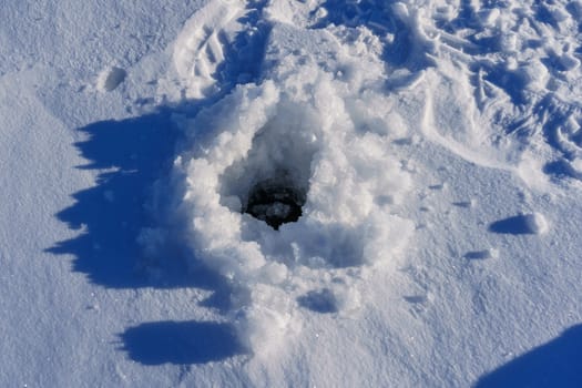 ice hole for fishing on a sunny winter day