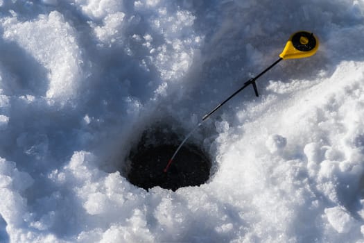 hole in the ice and a fishing rod for winter fishing, sunny day