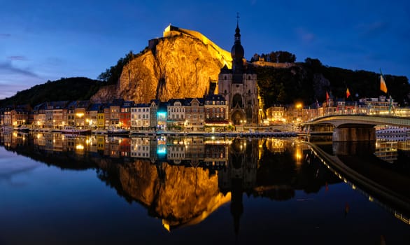 Night view of Dinant town, Collegiate Church of Notre Dame de Dinant over River Meuse and Pont Charles de Gaulle bridge and Dinant Citadel illuminated in the evening. Dinant, Belgium