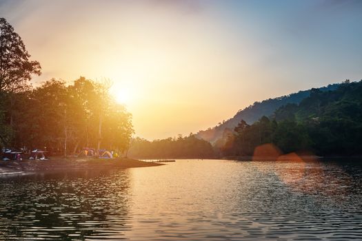 landscape of river view during the sunrise time with many colorful camping tent at campsite