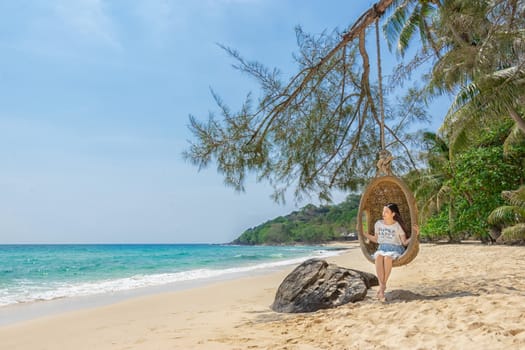happy traveler Asian woman relaxing on luxury swing and looking beautiful nature landscape beach. summer holiday vacation travel trip concept